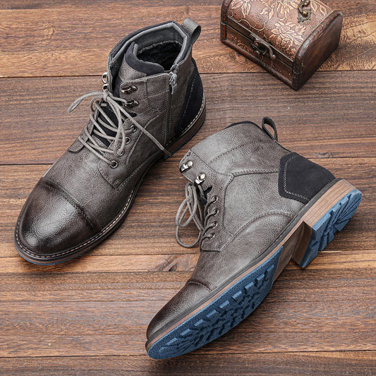 Pair of gray and black leather boots on a wooden surface with a decorative box.